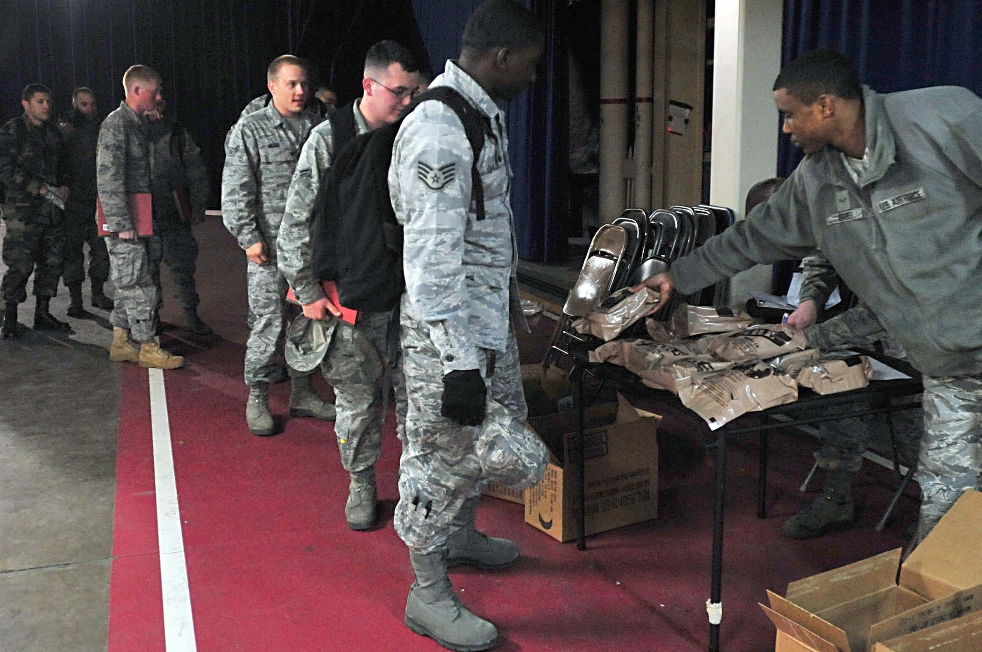 MISAWA AIR BASE, Japan -- Members of the 18th Civil Engineer Squadron from Kadena Air Force Base, line up to receive a meal ready to eat after their arrival Mar. 13. These members arrived to provide assistance with restoring electric power and other base recovery operation in support of disaster relief subsequent to Friday's earthquake. (U.S. Air Force photo by Staff Sgt. Marie Brown\Released)
