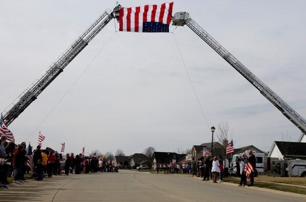 Local citizens lined the streets of a procession route to show support for Airman 1st Class Zachary Cuddeback and his family March 12, 2011 in O’Fallon, Ill. Airman Cuddeback and another Airman were killed March 2, 2011 when a man opened fire on a bus of U.S. Airmen at an airport in Frankfurt, Germany. Airman Cuddeback will be laid to rest next to his grandfather at a cemetery in O'Fallon, Ill. (U.S. Air Force photo/Staff Sgt. Brian J. Valencia)