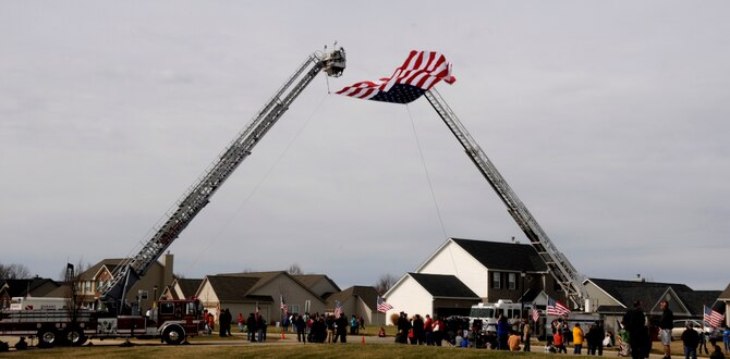 Local citizens lined the streets of a procession route to show support for Airman 1st Class Zachary Cuddeback and his family March 12, 2011 in O’Fallon, Ill. Airman Cuddeback and another Airman were killed March 2, 2011 when a man opened fire on a bus of U.S. Airmen at an airport in Frankfurt, Germany. Airman Cuddeback will be laid to rest next to his grandfather at a cemetery in O'Fallon, Ill. (U.S. Air Force photo/Staff Sgt. Brian J. Valencia)