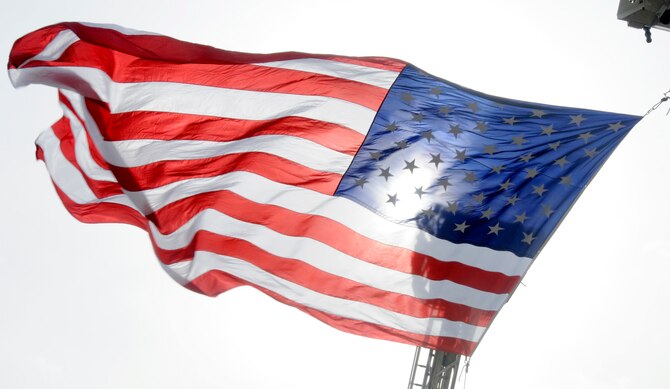 An American Flag waves high above the procession route of Airman 1st Class Zachary Cuddeback March 12, 2011 in O’Fallon, Ill. Airman Cuddeback and another Airman were killed March 2, 2011 when a man opened fire on a bus of U.S. Airmen at an airport in Frankfurt, Germany. Airman Cuddeback will be laid to rest next to his grandfather at a cemetery in O'Fallon, Ill. (U.S. Air Force photo/Staff Sgt. Brian J. Valencia)