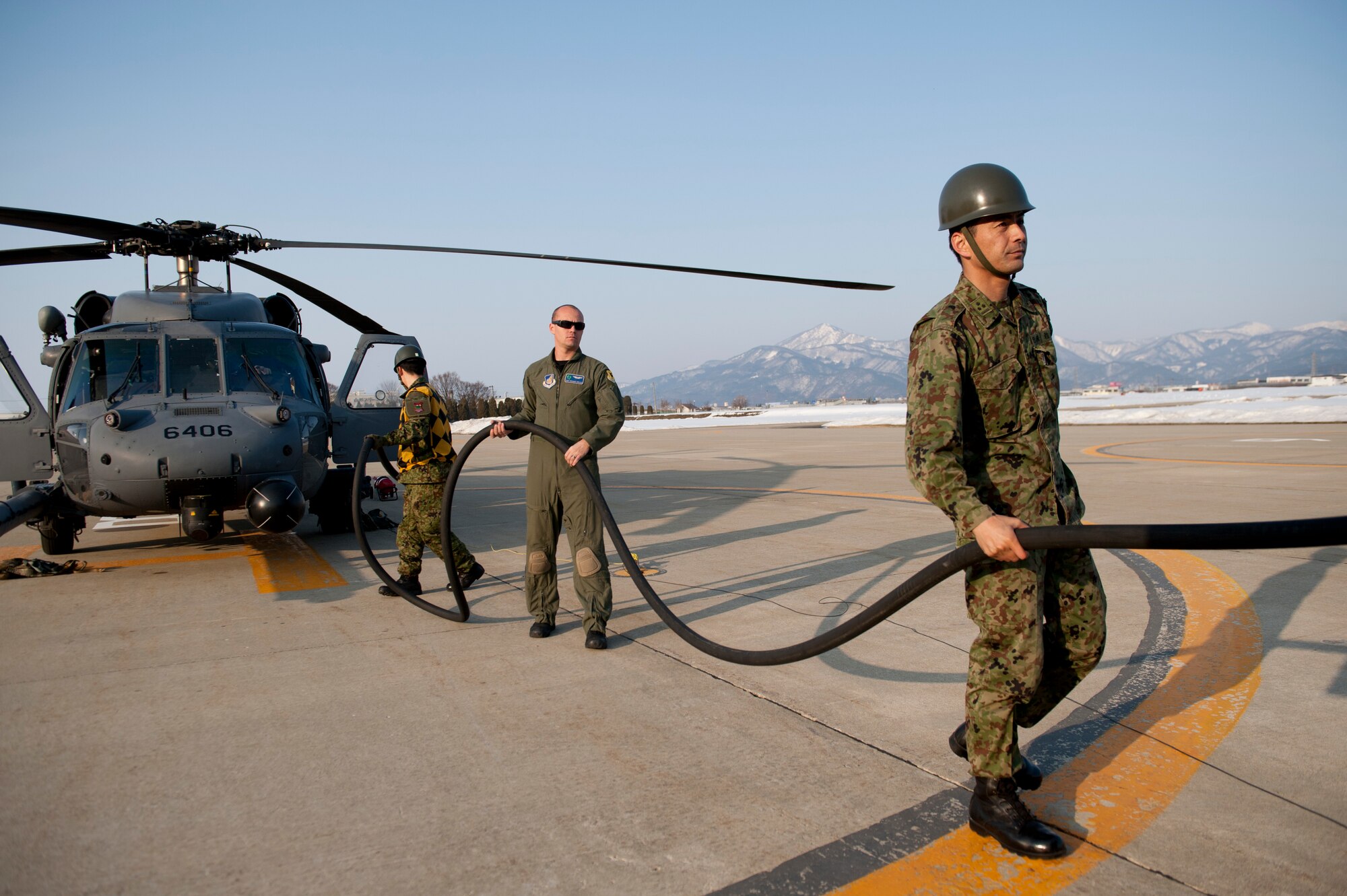 YAMAGATA, Japan -- Tech. Sgt. Michael Wells, 33rd Rescue Squadron aerial gunner, and members of the Japan Ground Self-Defense Force refuel an HH-60 Pave Hawk helicopter here March 13. Yamagata is a possible fuel staging area in support of Japan's earthquake and tsunami recovery efforts.  (U.S. Air Force photo/Staff Sgt. Samuel Morse)