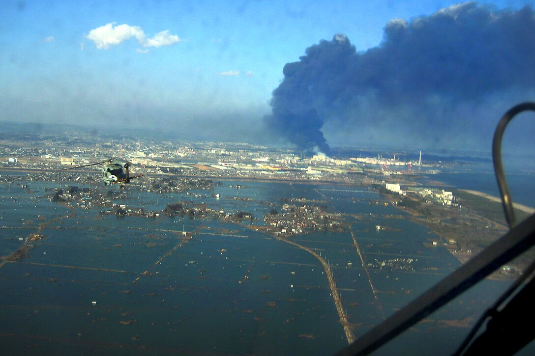 A helicopter flies over Sendai, Japan, March 13, 2011, to deliver more than 1,500 pounds of food to survivors of the 8.9 magnitude earthquake and  tsunami. The citizens of Ebina City, Japan, donated the food.