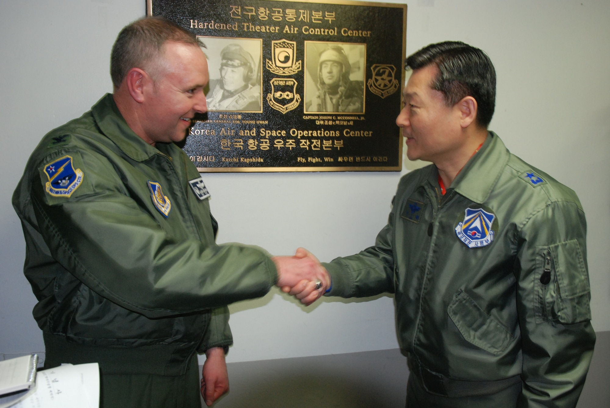 Col. James McGovern, U.S. Air Force 607th Air and Space Operations Center Commander and Gen. Won, In Choul, Air Operations Center Director for the Republic of Korea Air Forces shake hands March 10, 2011, at Osan Air Force Base, after unveiling a bronze plaque depicting the top U.S. and Republic of Korea Air Force aces during the Korean War.  