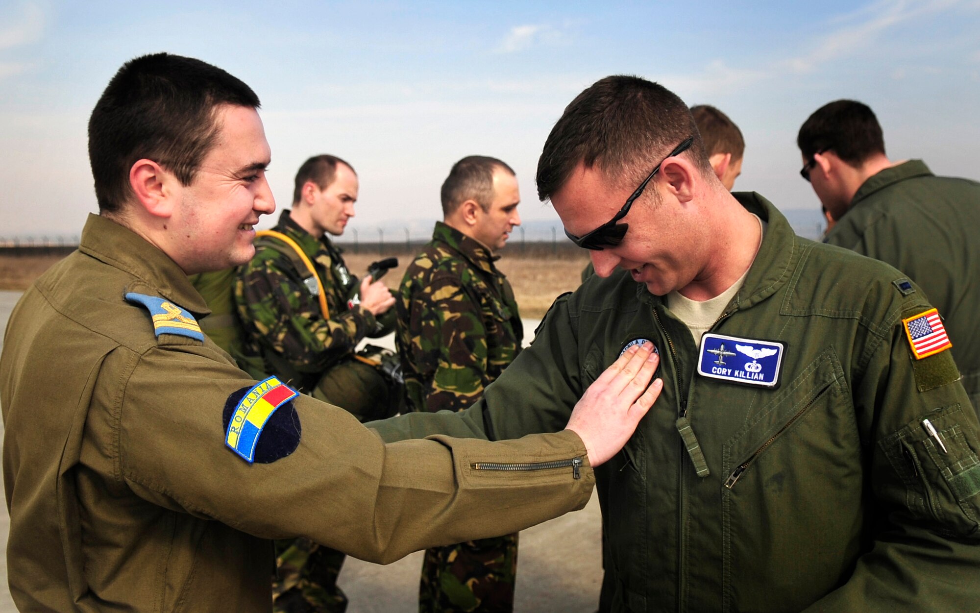 Romanian Air Force Lt. Daniel Motoroiu, pilot, exchanges a patch with U.S. Air Force 1st Lt. Cory Killian, 37th Airlift Squadron pilot, at Campia Turzii, Romania, March 14, 2011. Lieutenant Killian, introduced this tradition to Lieutenant Motoroiu after the first leg of their first flying mission of Carpathian Spring 2011, a building partnerships capacity exercise where members of the U.S. military join their Romanian counterparts to learn from one another and strengthen alliances. (U.S. Air Force Photo by Tech Sgt. Jocelyn L. Rich)