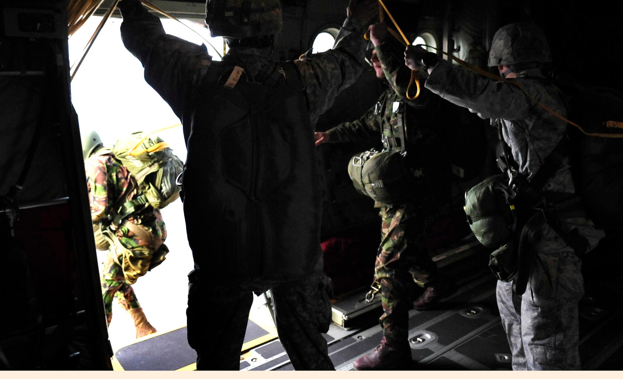 Romanian paratroopers exit a U.S. Air Force C-130J, as U.S. paratroopers serve as jump masters, over a landing zone near Campia Turzii, Romania, March 14, 2011.  The jump was performed on the first day of Carpathian Spring 2011, a building partnerships capacity exercise where members of the U.S. military join their Romanian counterparts to learn from one another and strengthen alliances. (U.S. Air Force Photo by Tech Sgt. Jocelyn L. Rich)