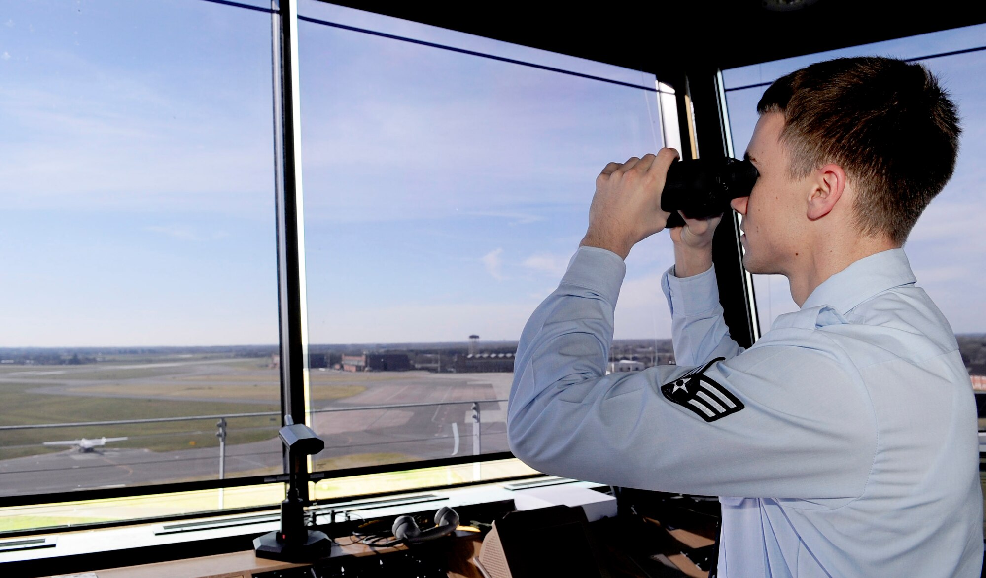 RAF MILDENHALL, England -- Senior Airman Zach Bickhaus, 100th Operations Support Squadron air traffic controller, makes visual confirmation of an incoming plane here March 14, 2011. Binoculars are used to ensure that the landing gear is down on approaching aircraft. (U.S. Air Force photo/Senior Airman Ethan Morgan)