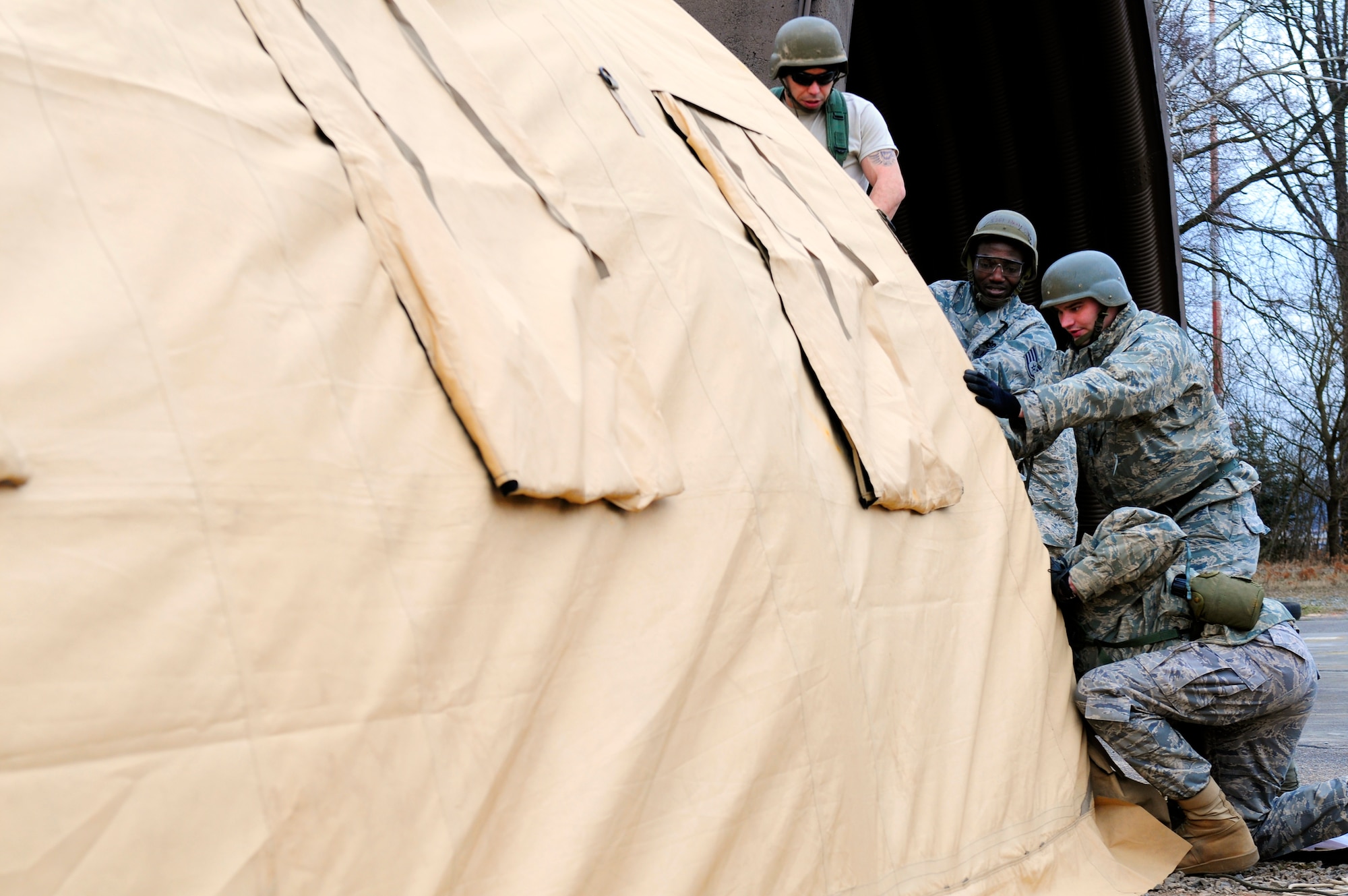 U.S. Air Force Airmen help erect a tent during the practical application exercise portion of Silver Flag, Ramstein Air Base, Germany, March 11, 2011. Silver Flag is a weeklong, training program that Airmen from all over the world participate in. Silver Flag combines classroom and practical application exercises to prepare airmen for deployment. (U.S. Air Force Photo by Airman 1st Class Brea Miller)