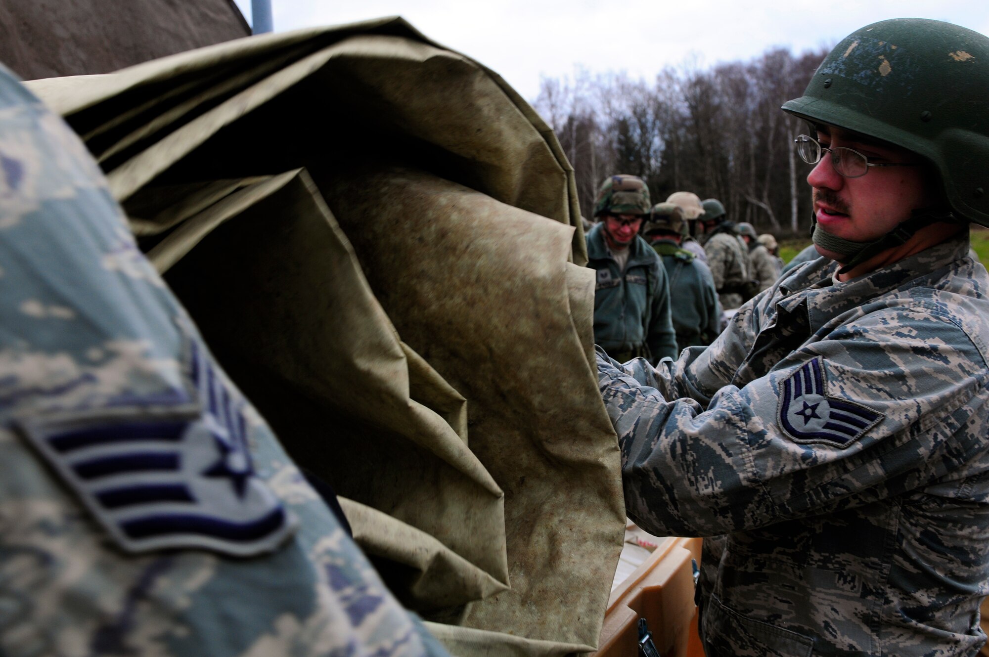 U.S. Air Force Airmen gather tent equipment before the practical application exercise portion of Silver Flag, Ramstein Air Base, Germany, March 11, 2011. Silver Flag is a weeklong, training program that Airmen from all over the world participate in. Silver Flag combines classroom and practical application exercises to prepare airmen for deployment. (U.S. Air Force Photo by Airman 1st Class Brea Miller)