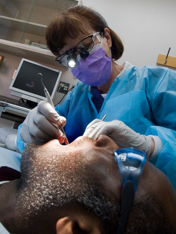Sharon Baker, Navy Dental Clinic dentist, performs an oral examination on Navy Cryptologic Technician 1st Class Tristan Mack, Naval Network Warfare Command, Norfolk, Va., at the Navy Dental Clinic March 8 prior to an upcoming deployment in support of Operation New Dawn in Iraq. (U.S. Air Force photo/Bobby Jones)