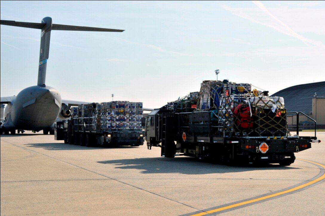 Loaders from the 89th Aerial Port Squadron move to a C-17 Globemaster III to unload rescue equipment bound for Japan on March 12, 2011, at Joint Base Andrews, Md.  Air transportation Airmen from the 89th APS created 14 pallets of technical search and rescue gear, to include inflatable swift-water rescue boats, generators, trench rescue and cutting equipment. The gear is being transported by C-17 to more than 80 Fairfax County Urban Search and Rescue technicians, to provide assistance in the rescue effort after an earthquake and tsunami hit Japan on March 11, 2011. (U.S. Air Force Photo/Senior Airman Perry Aston) 