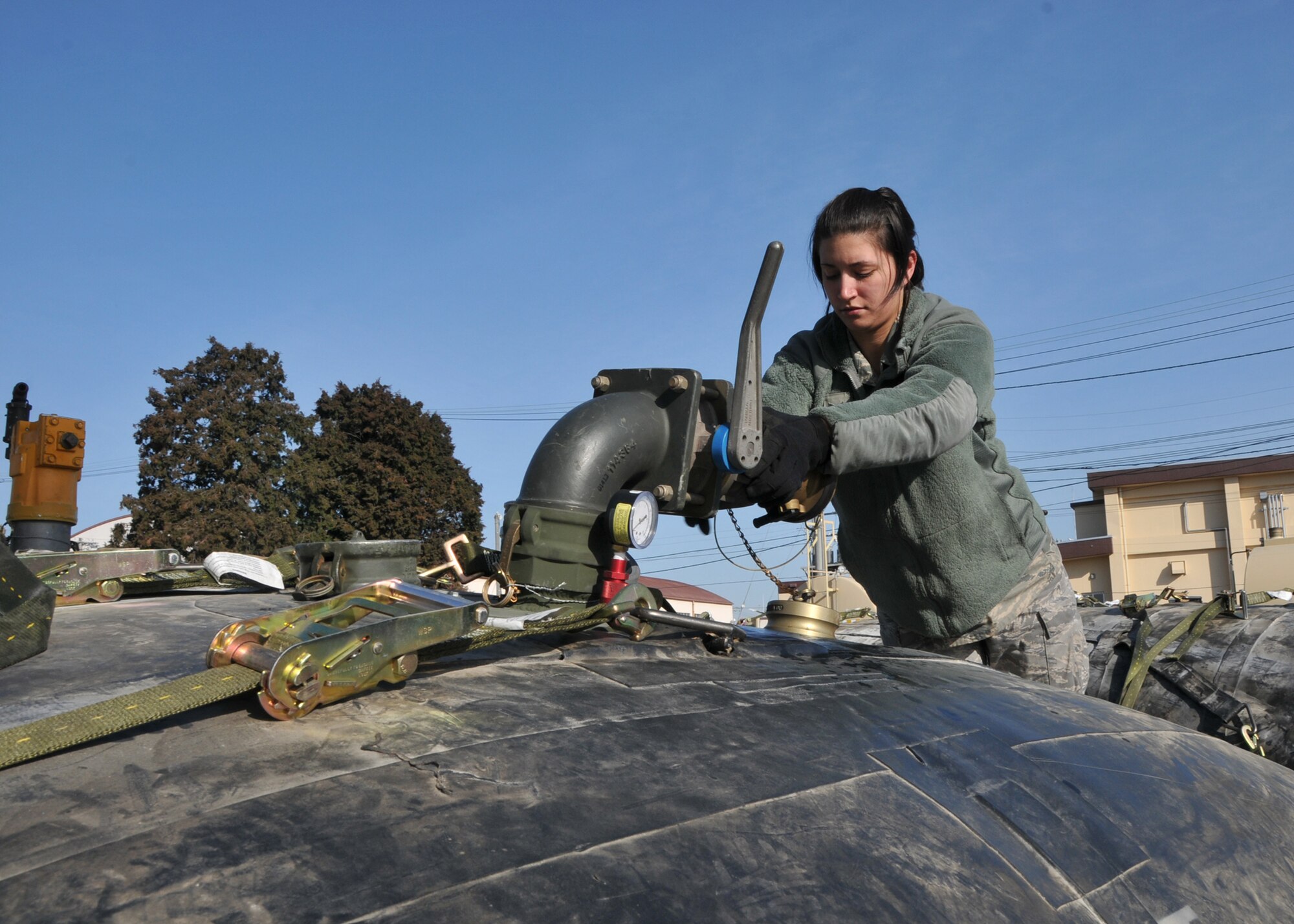 YOKOTA AIR BASE, Japan -- Senior Airman Sarah Bishop, 374th Logistics Readiness Squadron force support equipment operator, seals a fuel bladder valve here, on March 14. The fuel bladders were checked and prepared for transit to support forward aircraft providing relief to Japanese citizens affected by the earthquake and tsunami on the east coast of Japan, on March 11.  (U.S. Air Force photo/Airman 1st Class Andrea Salazar)