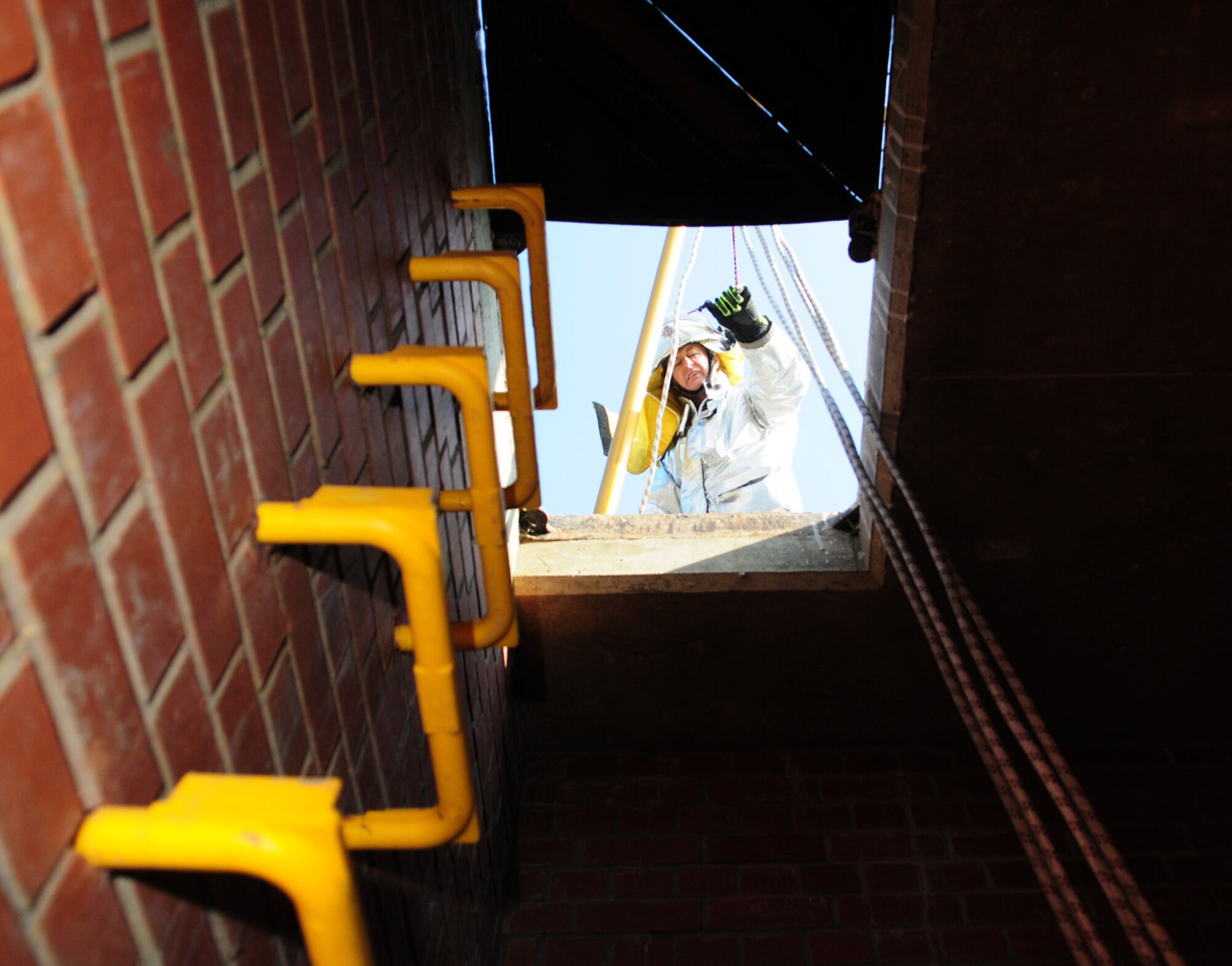 RAF MILDENHALL, England -- Firefighter Andrew Nash, 100th Civil Engineer Squadron Fire Department, sets up a tripod and mechanical hauling system on top of the confined space trainer March 8, 2011, during a training session. (U.S. Air Force photo/Karen Abeyasekere)
