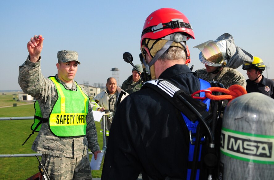 RAF MILDENHALL, England -- Tech. Sgt. Jake Silvia, 100th Civil Engineer Squadron Fire Department, gives a safety briefing to firefighters preparing to enter the confined space trainer here March 8, 2011, as part of a training exercise. The new trainer gives firefighters the ability to practice moving vertically if the main steps are out of use. It also enables firefighters to create new ways of reaching victimes and lowering them from the top of a platform to rescuers and medics on the ground. For this exercise,  two firefighters used a ladder to go down inside the confined space, but pulled the victim out of the hole and to safety by using a mechanical haul system on a tripod, which was put together by other firefighters above ground. (U.S. Air Force photo/Karen Abeyasekere)
