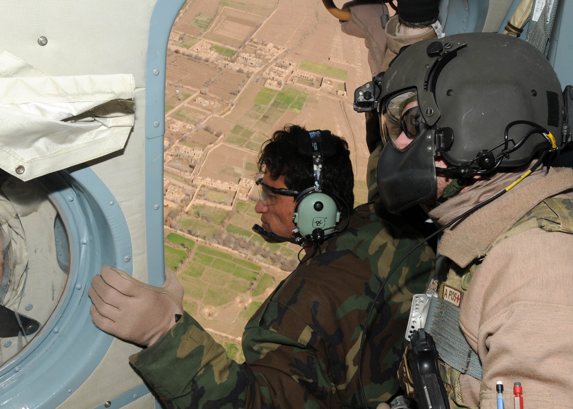 SHINDAND, Afghanistan - Afghan Air Force Staff Sgt. Mohammad Shafi, one of the Afghan flying crew chief students, make sure the Mi-17 is clear while Tech. Sgt. Travis Willingham, a flying crew chief air advisor, helps advise Staff Sgt. Shafi during his first flight mission at Shindand, Afghanistan. (U.S. Navy photo by Mass Communications Specialist 3rd Class Jared E. Walker). 