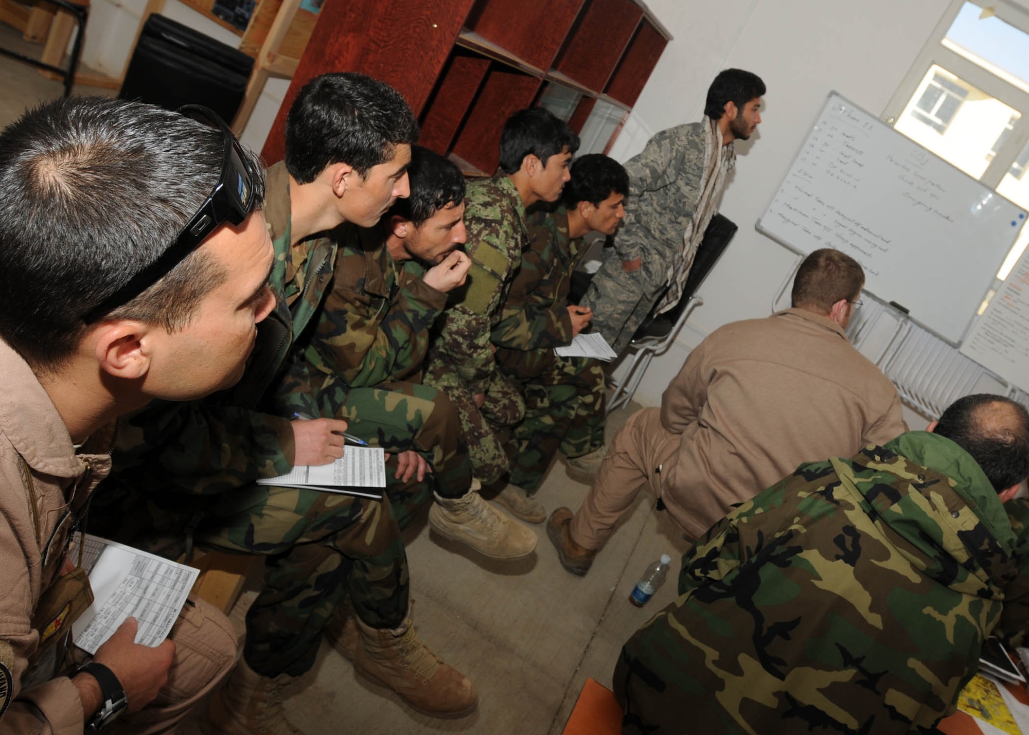 SHINDAND, Afghanistan - Staff Sgt. Christopher A. Morford, Flying Crew Chief Advisor, stationed out of Davis Monthan Air Force Base, sits with the four students of the flying air crew chiefs during a brief of the upcoming flight mission at Shindand, Afghanistan. (U.S. Navy photo by Mass Communications Specialist 3rd Class Jared E. Walker).
