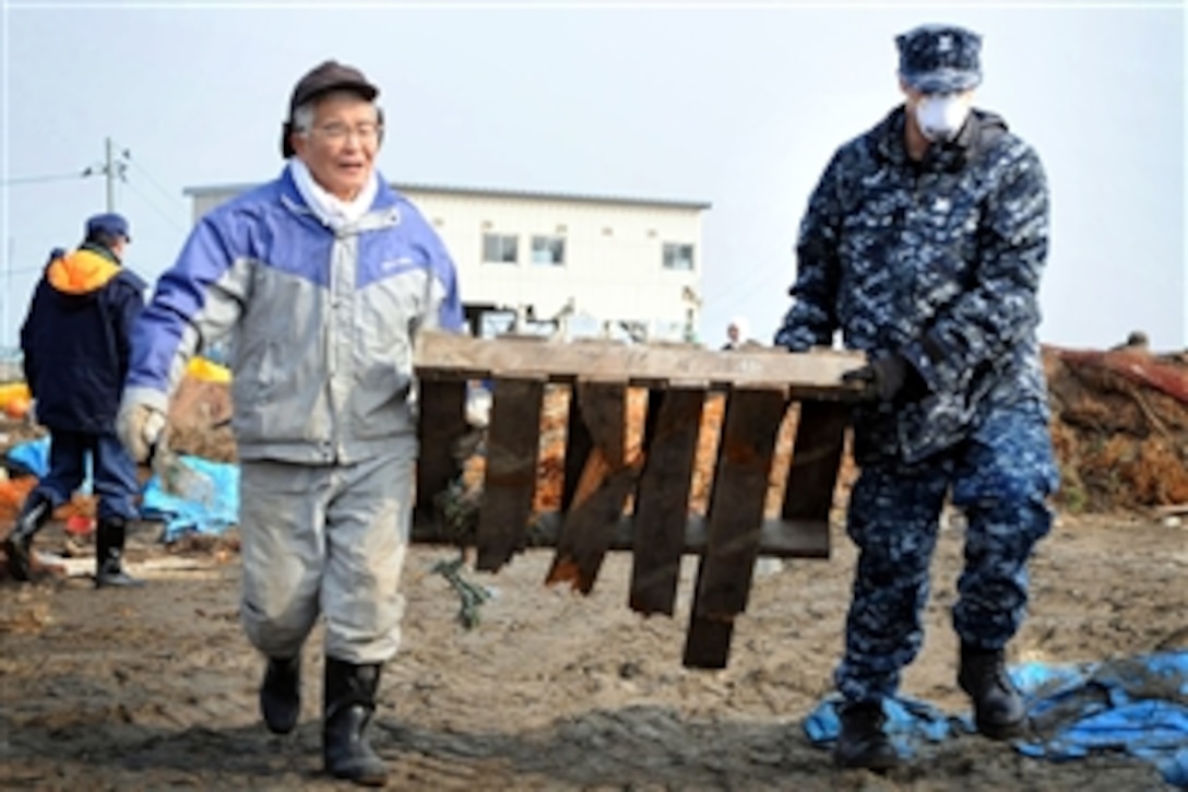 U.S. Navy Petty Officer 2nd Class John Dicola, assigned to Naval Air Facility Misawa, Japan, helps remove debris during a cleanup effort at the fishing port in Misawa, March 14, 2011. More than 90 sailors from the facility volunteered to work with Misawa city employees and members of the local community.