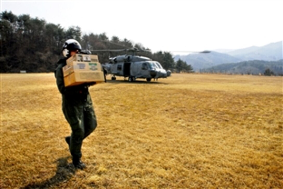 U.S. Navy Petty Officer 2nd Class Brian Fox carries humanitarian relief supplies to Japanese aid workers in Takihana, Japan, March 13, 2011. Fox is assigned to the helicopter anti-submarine squadron embarked aboard USS Ronald Reagan.