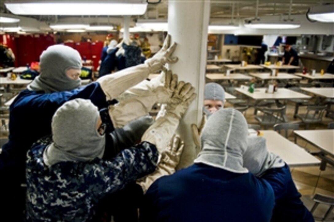 U.S. Navy sailors on the mess deck of the aircraft carrier USS Carl Vinson brace for impact during a general quarters drill in the Arabian Sea, March 12, 2011. The Carl Vinson Carrier Strike Group is deployed to support maritime security operations and theater security cooperation efforts in the U.S. 5th Fleet area of responsibility.