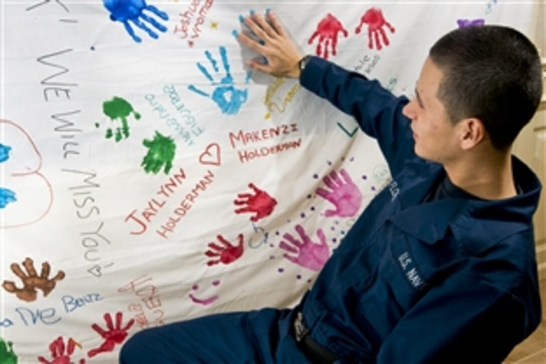 U.S. Navy Seaman Salvador Flores reads greetings from family members in the museum aboard USS Carl Vinson in the Arabian Sea., March 14, 2011. The Carl Vinson Carrier Strike Group is deployed supporting maritime security operations and theater security cooperation efforts in the U.S. 5th Fleet area of responsibility. Flores is an aviation ordnanceman airman assigned to the weapons department of the aircraft carrier USS Carl Vinson.