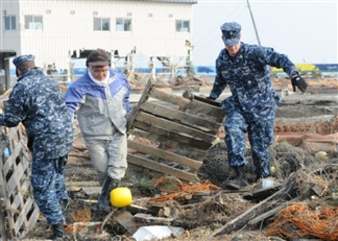 Chief Petty Officer Kyle Wilkinson (right), from Baldwinsville, N.Y., assigned to Naval Air Facility Misawa, helps remove debris during a cleanup effort at the Misawa Fishing Port on March 14, 2011.  More than 90 sailors from Naval Air Facility Misawa volunteered to help Misawa City employees and members of the community begin to clean up after an earthquake and tsunami.  