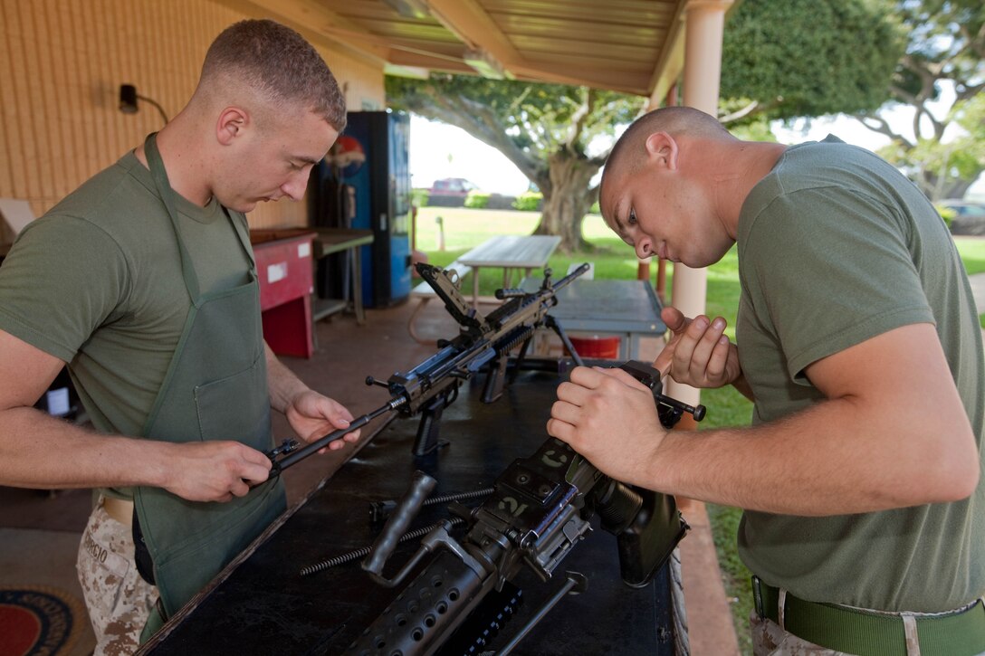 Pfc. Michael Curcio (left), an armorer with Headquarters and Service Battalion, U.S. Marine Corps Forces, Pacific, and Lance Cpl. Zachary Morphew, an armory custodian with the unit, conduct routine maintenance on M249 Squad Automatic Weapons here March 15.