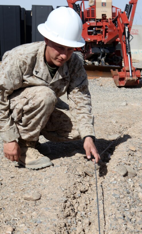 Corporal Steven Culp, the assistant wire chief for the Communication Platoon with Regimental Combat Team 8, inspects a buried wire aboard Forward Operating Base Delaram II, Afghanistan, March 15.  Culp is currently working a position that is intended for a Marine two ranks senior to him.