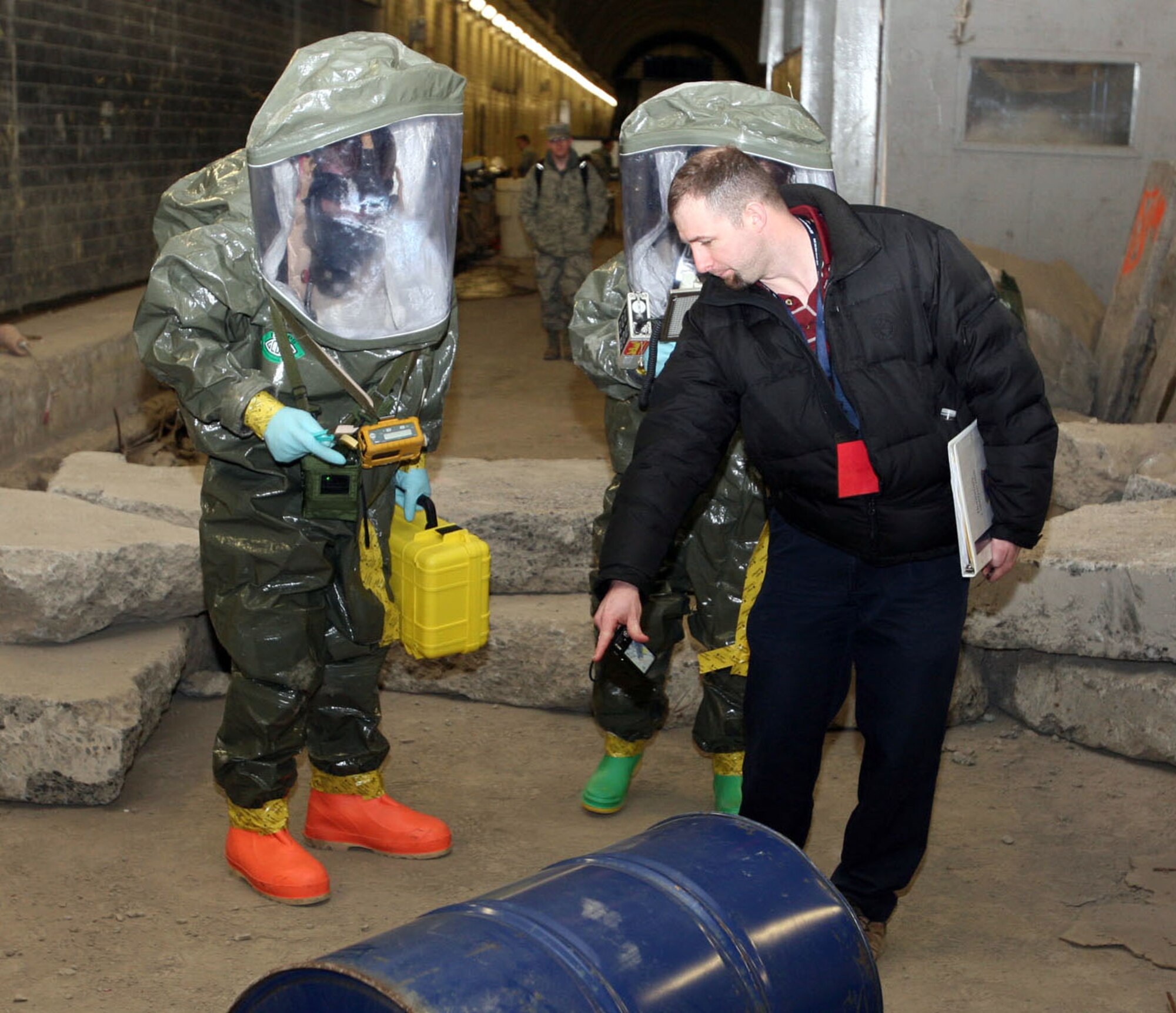 Mr. Joe Potaczek, a cadre member, points to a mysterious liquid seeping from a barrel as Senior Airman Emily Zaronczyk (left) uses M-8 paper to detect the nature of a liquid seeping from a drum during Integrated Base Emergency Response Capability Training at the Center for National Response in Gallagher, W.V., on Feb. 28, 2011. The exercise, held Feb. 28 to March 4, 2011, was the first time Air Mobility Command bioenvironmental engineering and emergency management came together to hone their emergency response skills in a controlled training environment.  (U.S. Air Force Photo/Lt. Col. David Lester)