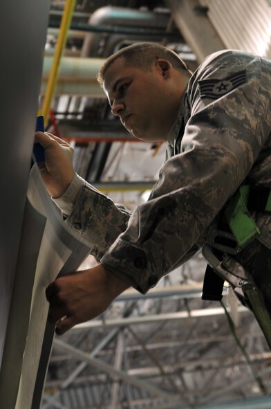 MINOT AIR FORCE BASE, N.D. -- Staff Sgt. Adam Lewis, 5th Maintenance Squadron aircraft structural maintenance craftsman, puts the finishing touches on a decal on the side of a B-52H Stratofortress, here March 11. This was the first jet at Minot to receive the decals instead of being painted.  (U.S. Air Force photo/Airman 1st Class Jessica McConnell)