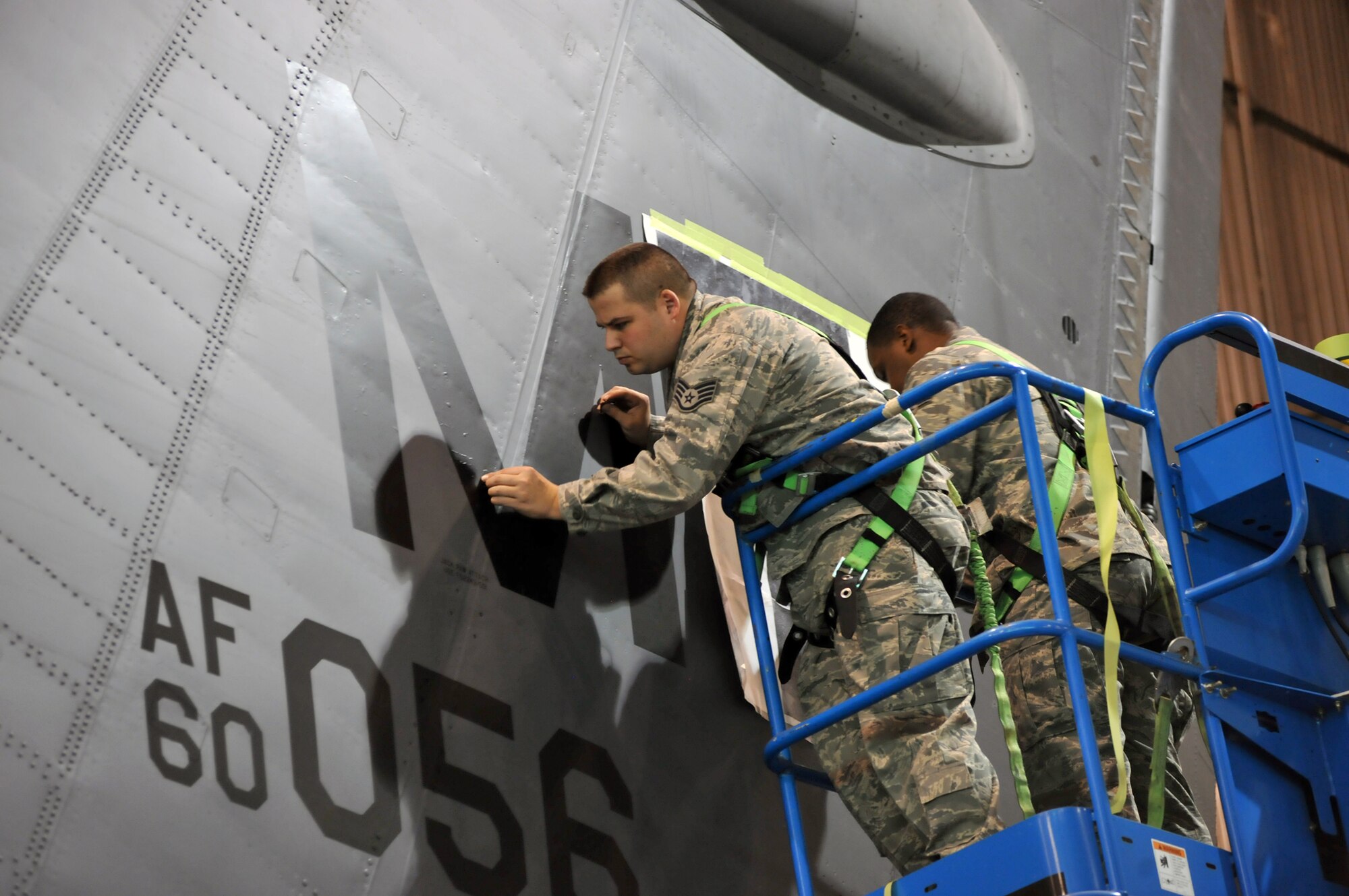 MINOT AIR FORCE BASE, N.D. -- Staff Sgt. Adam Lewis, 5th Maintenance Squadron aircraft structural maintenance craftsman, and Senior Airman Jerrett Parker, 5th MXS aircraft structural maintenance journeyman, work on the Minot AFB designator decal on the tail section of a B-52H Stratofortress here March 11. This was the first jet at Minot to receive the decals instead of being painted. (U.S. Air Force photo/Staff Sgt. Keith Ballard)