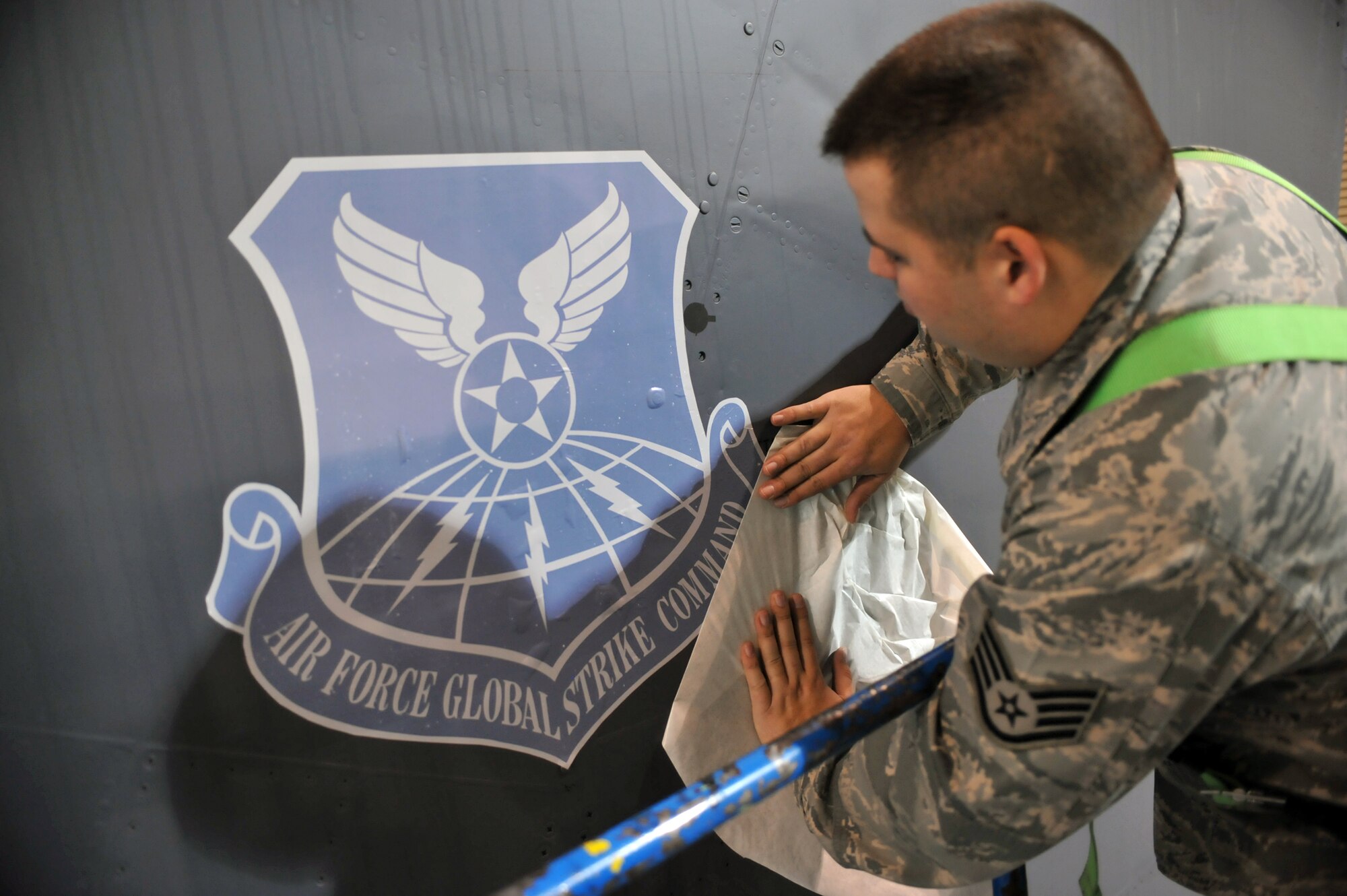 MINOT AIR FORCE BASE, N.D. -- Staff Sgt. Adam Lewis, 5th Maintenance Squadron aircraft structural maintenance craftsman, peels the backing off of the Air Force Global Strike Command decal on the tail section of a B-52H Stratofortress, here March 11. This was the first jet at Minot to receive the decals instead of being painted. (U.S. Air Force photo/Staff Sgt. Keith Ballard)