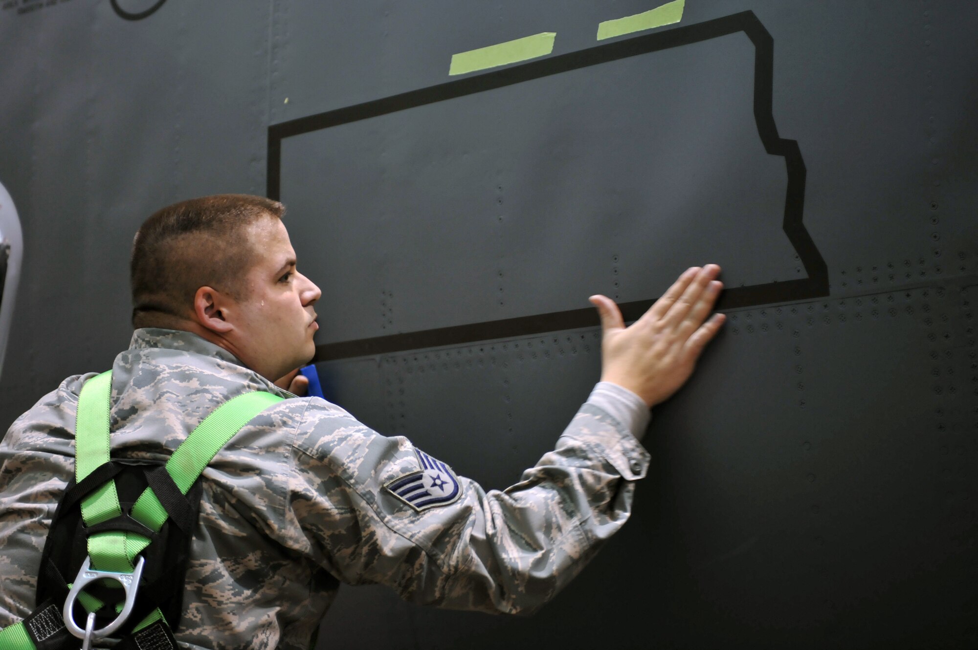 MINOT AIR FORCE BASE, N.D. -- Staff Sgt. Adam Lewis, 5th Maintenance Squadron aircraft structural maintenance craftsman, puts the finishing touches on the state of North Dakota decal on the side of a B-52H Stratofortress, here March 11. This was the first jet at Minot to receive the decals instead of being painted. (U.S. Air Force photo/Staff Sgt. Keith Ballard)