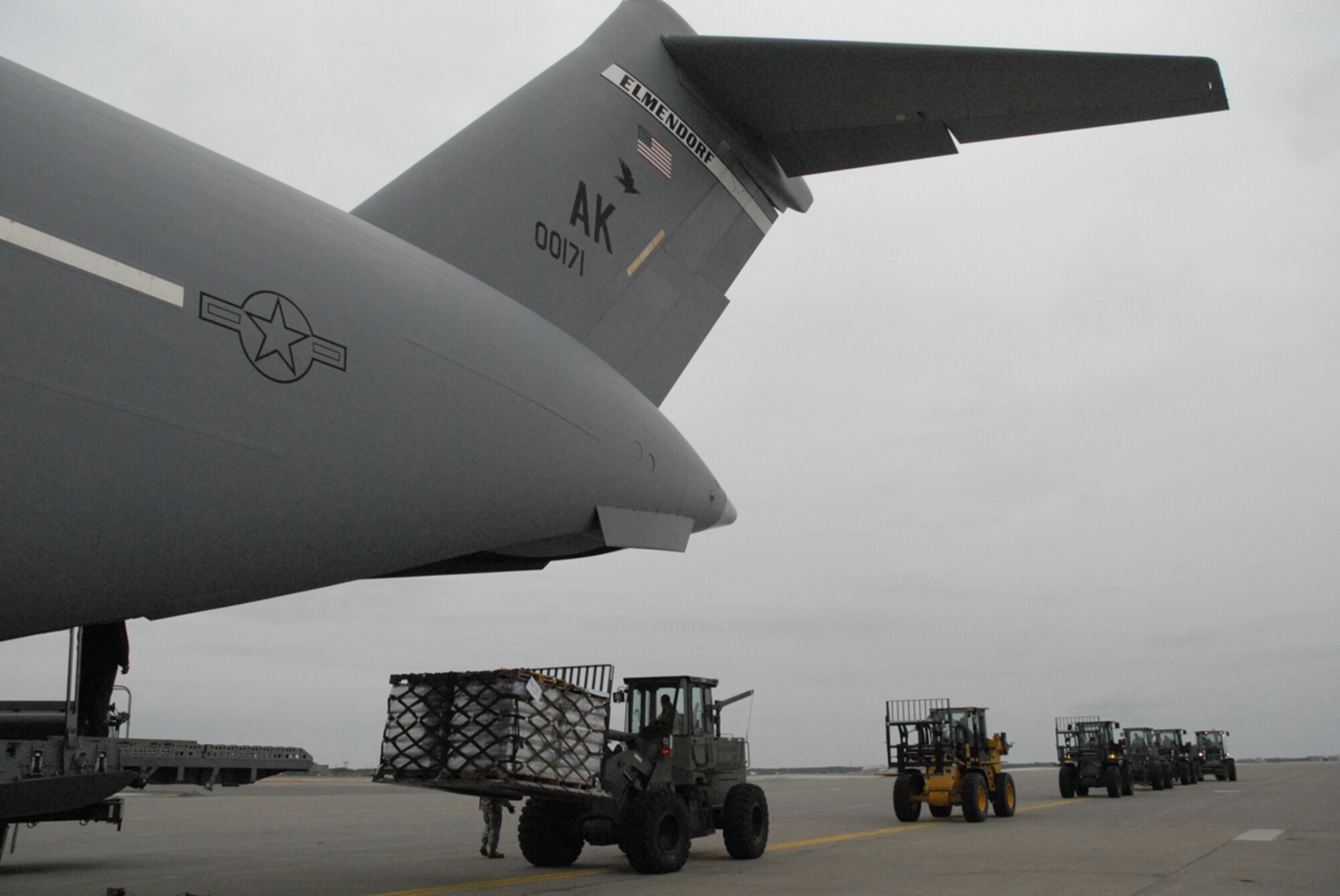 Joint Base Elmendorf-Richardson, Alaska -- Air Force Master Sgt. Stephen Mallory, loadmaster, stationed at the 517th Airlift Squadron, Joint Base Elmendorf Richardson Alaska, marshals 10KAT forklifts to offload 47,000 lbs of water for humanitarian relief efforts off a C-17 at Misawa Air Base, Japan. (U.S. Air Force photo/Staff Sgt. Mark Leahy)