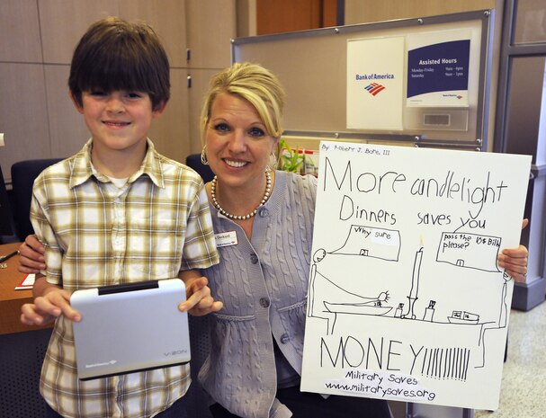 Jenna Deckard from the Bank of America Military Branch presents eight-year-old Robert Bare III, a new DVD player March 11 at the Bank of America Military Branch on Joint Base Charleston. Robert won the JB CHS poster contest for Military Saves Week. Robert is the son of Master Sgt. Maria Bare, from the 628th Civil Engineer Squadron. (U.S. Air Force photo/Master Sgt. Maria Bare)
