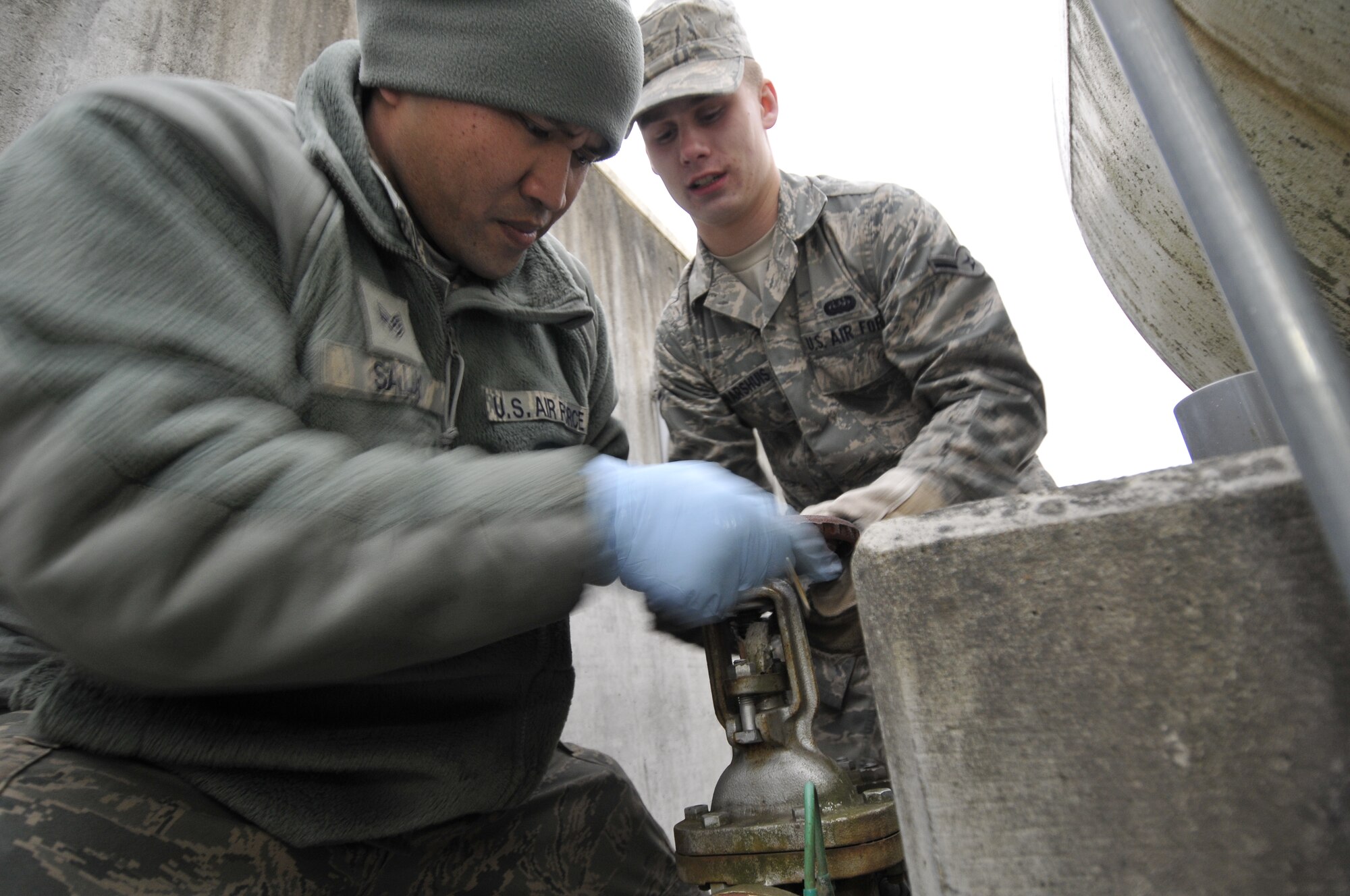 MISAWA AIR BASE, Japan -- Airman Evan Dwarshuis, 35th Communications Squadron cyber transport technician and Staff Sgt. Michael Salas, 35th Logistics Readiness Squadron fuels distribution supervisor, twist on a rusty fuel tank inlet valve Mar. 15. Airman Dwarshis is part of the 35th Fighter Wing’s augmentation force. The AUGFOR is a group of Airmen that assist other base agencies with work that requires more people than the agency has on hand. (U.S. Air Force Tech. Sgt. Phillip Butterfield\Released) 
