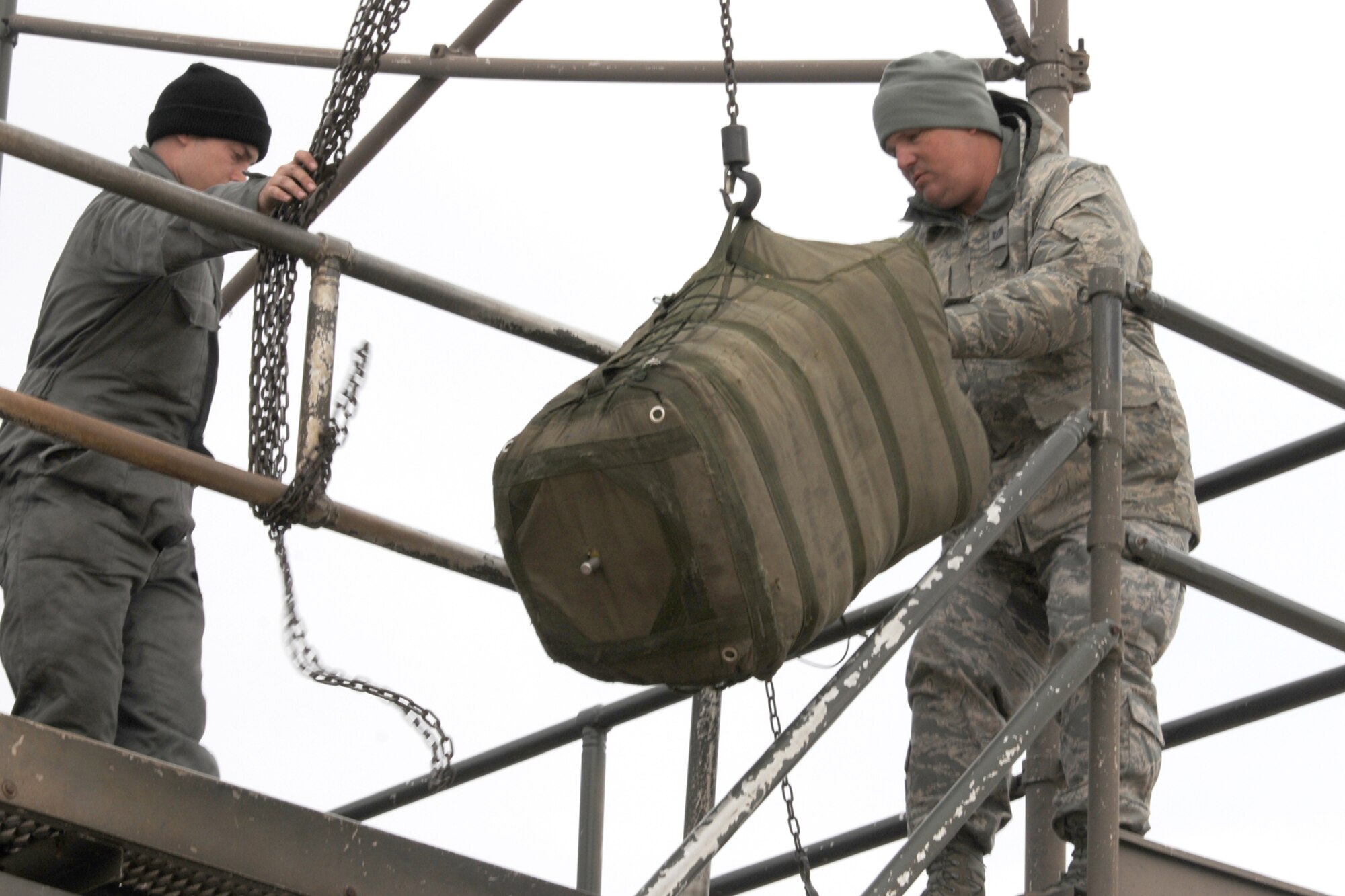 Airman 1st Class Justin Foster, a 20th Aircraft Maintenance Squadron crew chief, works the chains on a B-52 Drag Chute Maintenance Stand as Tech. Sgt. Tobin Young, a 707th Maintenance Squadron crew chief, guides a drag chute up for replacement in a 2nd Bomb Wing B-52H that has just returned from a nuclear training mission at Barksdale Air Force Base, La, March 5, 2011. The 707th MXS is an Air Force Reserve classic associate unit assigned to the 2nd Maintenance Group and supports the 343rd Bomb Squadron. The launch of this crew and aircraft was significant for being the first supported by 2nd BW operations and maintenance personnel during a 307th Bomb Wing Reserve Unit Training Assembly. (U. S. Air Force Photo/Master Sgt. Greg Steele)