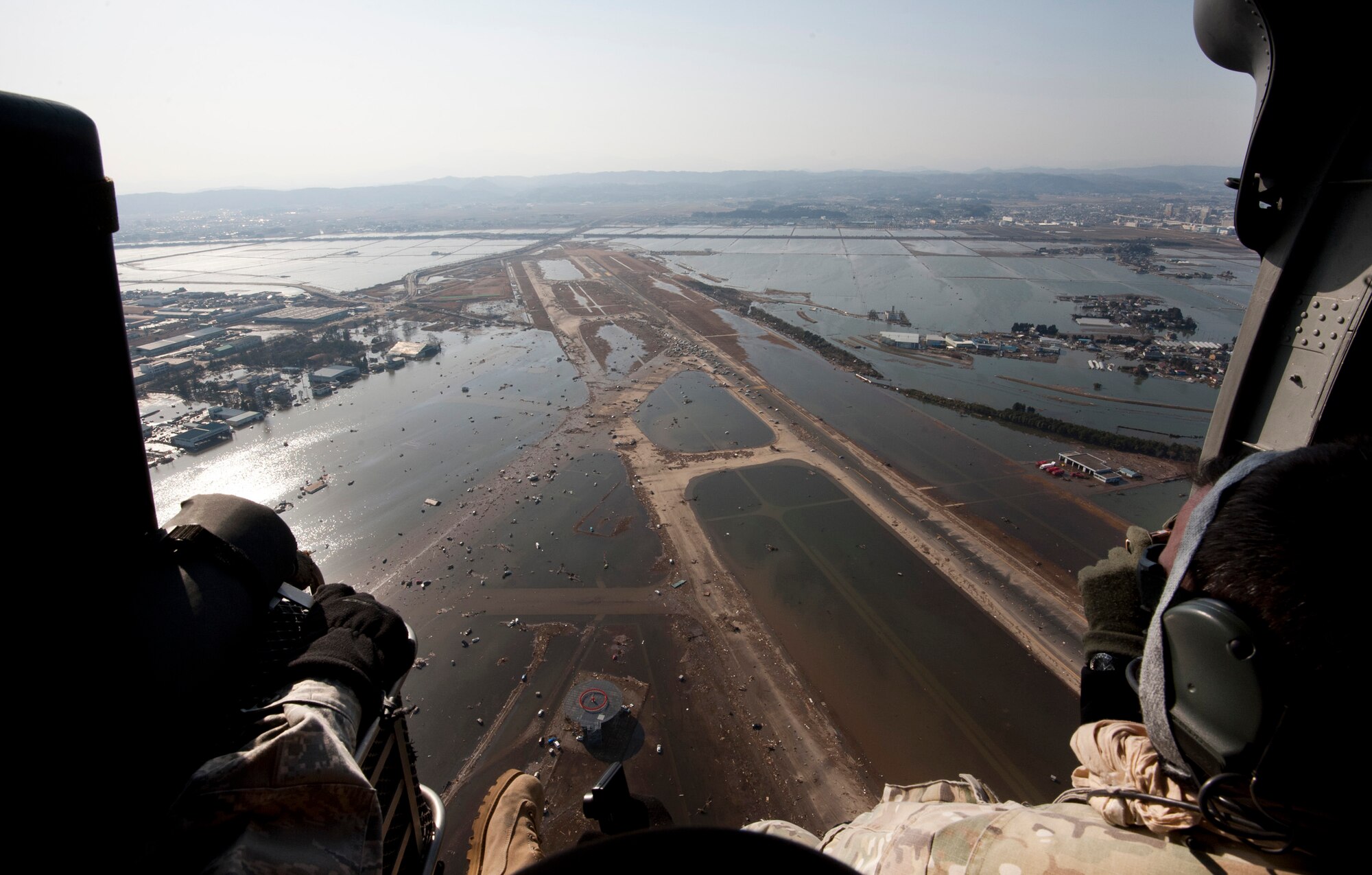 YOKOTA AIR BASE, Japan -- Air Force and Marine airlift and rescue leadership look out over the debris left at Sendai Airport, Japan, following a massive earthquake and subsequent tsunami March 11. The small dots covering the runway are vehicles left there after the tsunami water receded. (U.S. Air Force photo/Staff Sgt. Samuel Morse)