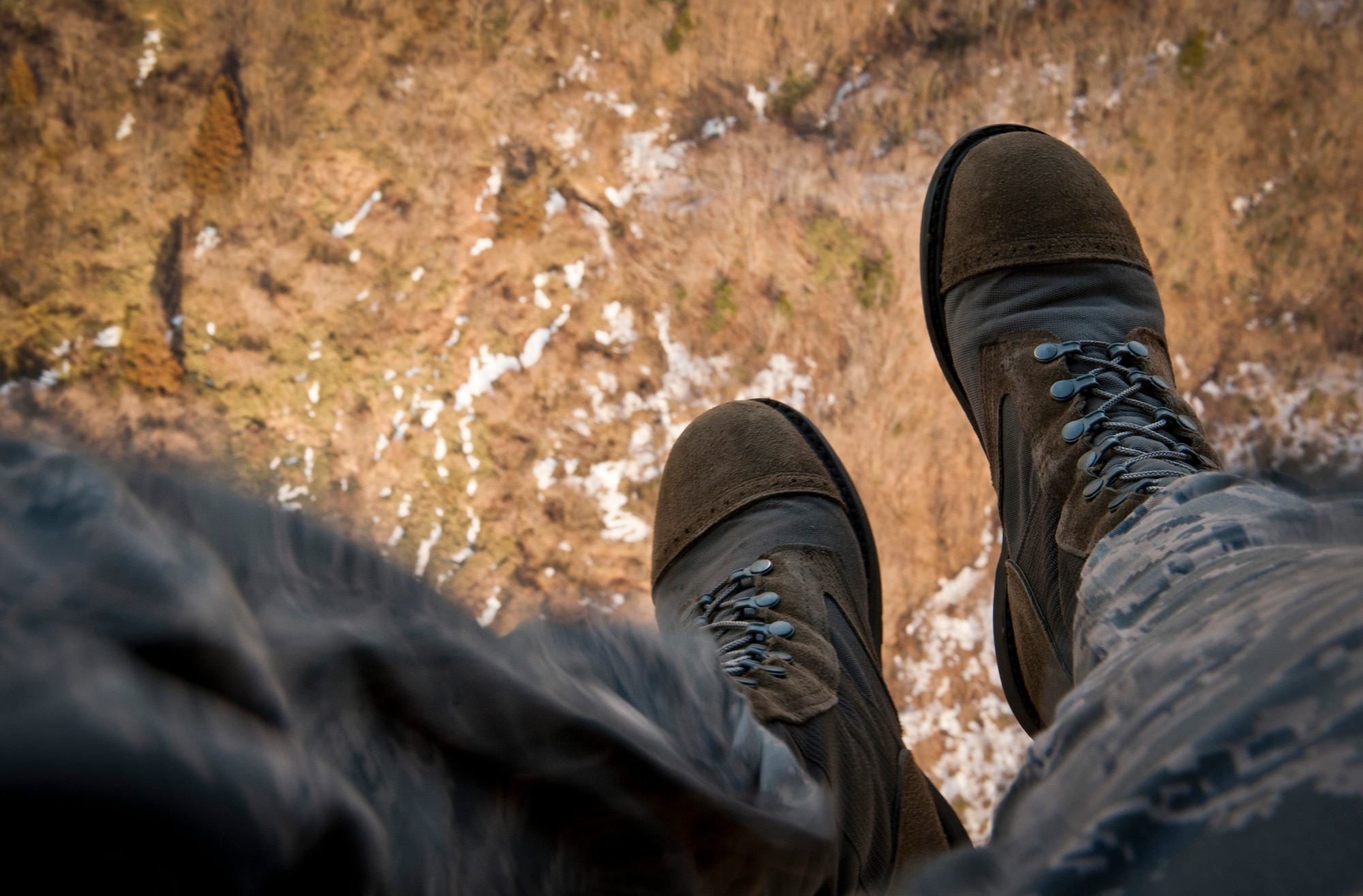 YOKOTA AIR BASE, Japan -- A pair of combat boots hang over the edge of an HH-60G Pave Hawk as it soars above the mountains of Japan March 13. The height and lingering capability of helicopters give military leadership broader perspective to help make critical decisions. (U.S. Air Force photo/Staff Sgt. Samuel Morse)