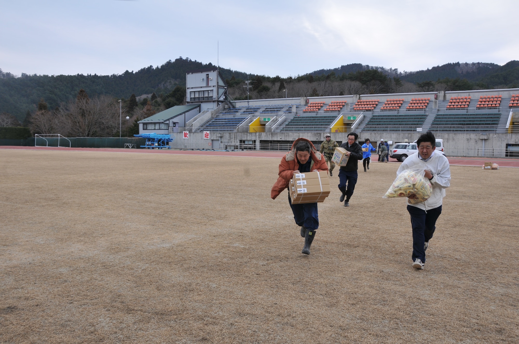 SENDAI, Japan -- Japanese citizens rush donated food and supplies to an awaiting U.S. Air Force HH-60G Pave Hawk helicopter March 14. (U.S. Air Force photo/Airman 1st Class Katrina R. Menchaca)
