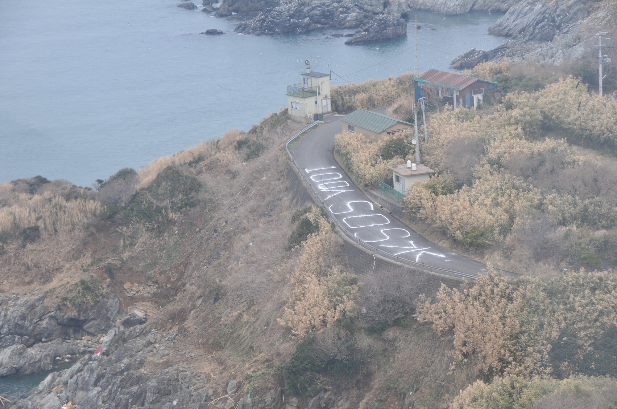 SENDAI, Japan -- U.S. Air Force search and rescue personnel observe a universal "SOS" sign on a coastal roadway in northeastern Japan March 14. The HH-60G helicopter crew are part of the American disaster relief forces here to assist with Japan's earthquake and tsunami recovery effort. (U.S. Air Force photo/Airman 1st Class Katrina R. Menchaca)