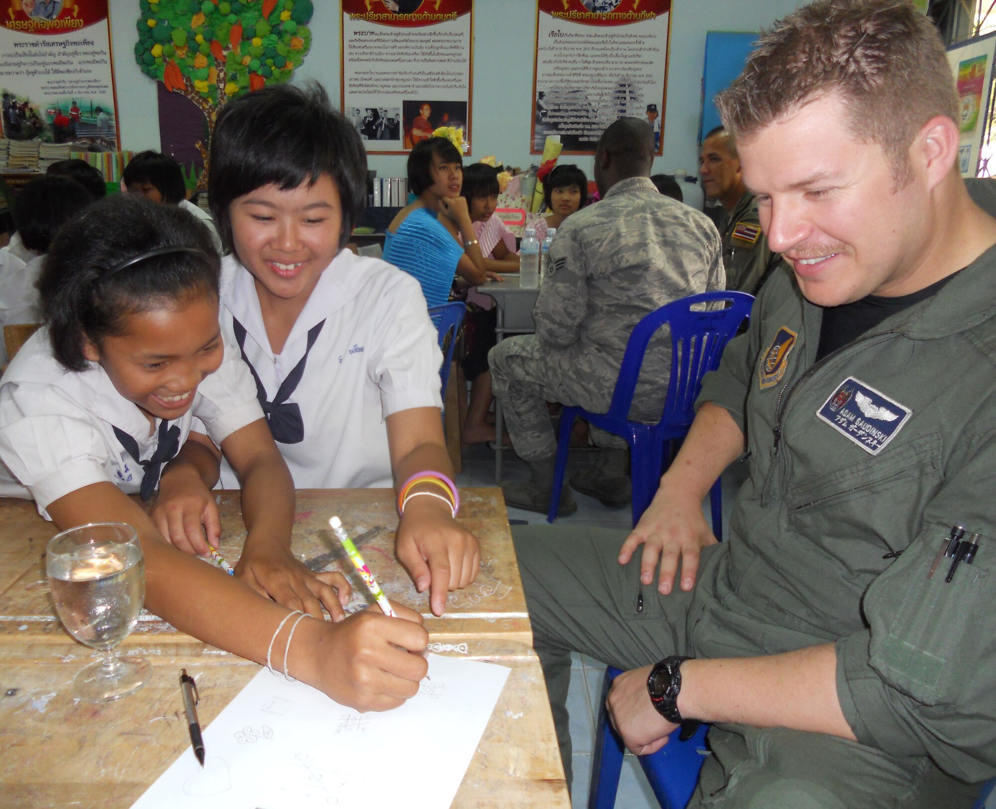 KORAT, Thailand - Capt. Adam Gaudinski, an F-15 pilot with the 44th Fighter Squadron at Kadena Air Base, Japan, and Nine Juntaporn and Tum Doungporn, students from Ang Huay Yang School March 14 in Korat, Thailand, enjoy a game of tic-tac-toe.  Airmen visited the school with members of the Royal Thai and Republic of Singapore Air Forces during Cope Tiger 2011, an annual, multilateral, joint field training exercise currently being conducted in Thailand March 14 through 25. (U.S. Air Force Photo/ Capt. Kirsten Udd)