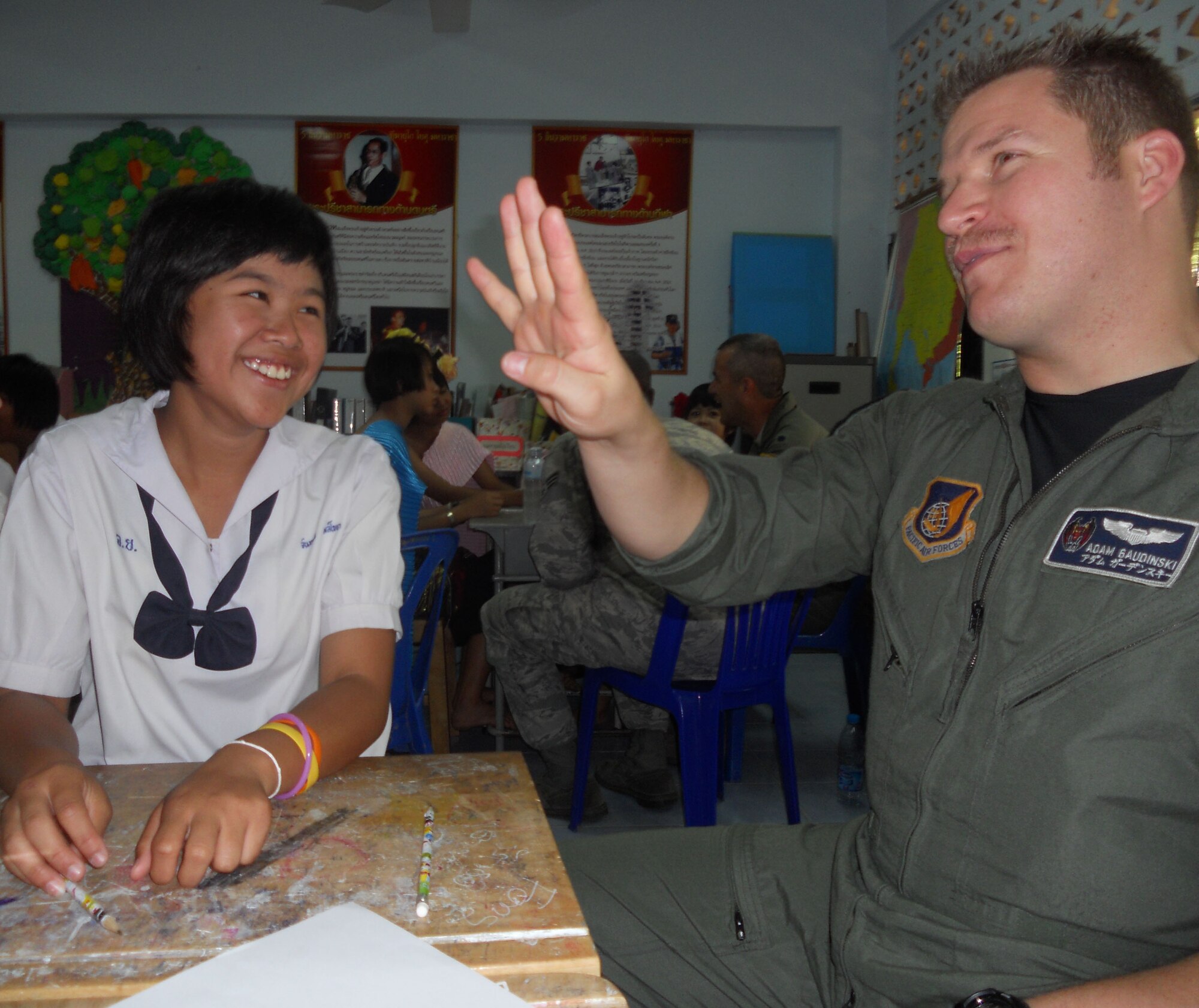KORAT, Thailand - Capt. Adam Gaudinski, an F-15 pilot stationed at Kadena Air Base, Japan, learns to say his numbers in Thai with Nine Juntaporn, a student from Ang Huay Yang School in Korat, Thailand, March 14.  Airmen visited the school with members of the Royal Thai and Republic of Singapore Air Forces during Cope Tiger 2011, an annual, multilateral, joint field training exercise currently being conducted in Thailand March 14 through 25. (U.S. Air Force Photo/ Capt. Kirsten Udd)