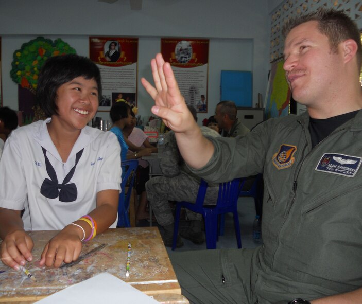 KORAT, Thailand - Capt. Adam Gaudinski, an F-15 pilot stationed at Kadena Air Base, Japan, learns to say his numbers in Thai with Nine Juntaporn, a student from Ang Huay Yang School in Korat, Thailand, March 14.  Airmen visited the school with members of the Royal Thai and Republic of Singapore Air Forces during Cope Tiger 2011, an annual, multilateral, joint field training exercise currently being conducted in Thailand March 14 through 25. (U.S. Air Force Photo/ Capt. Kirsten Udd)