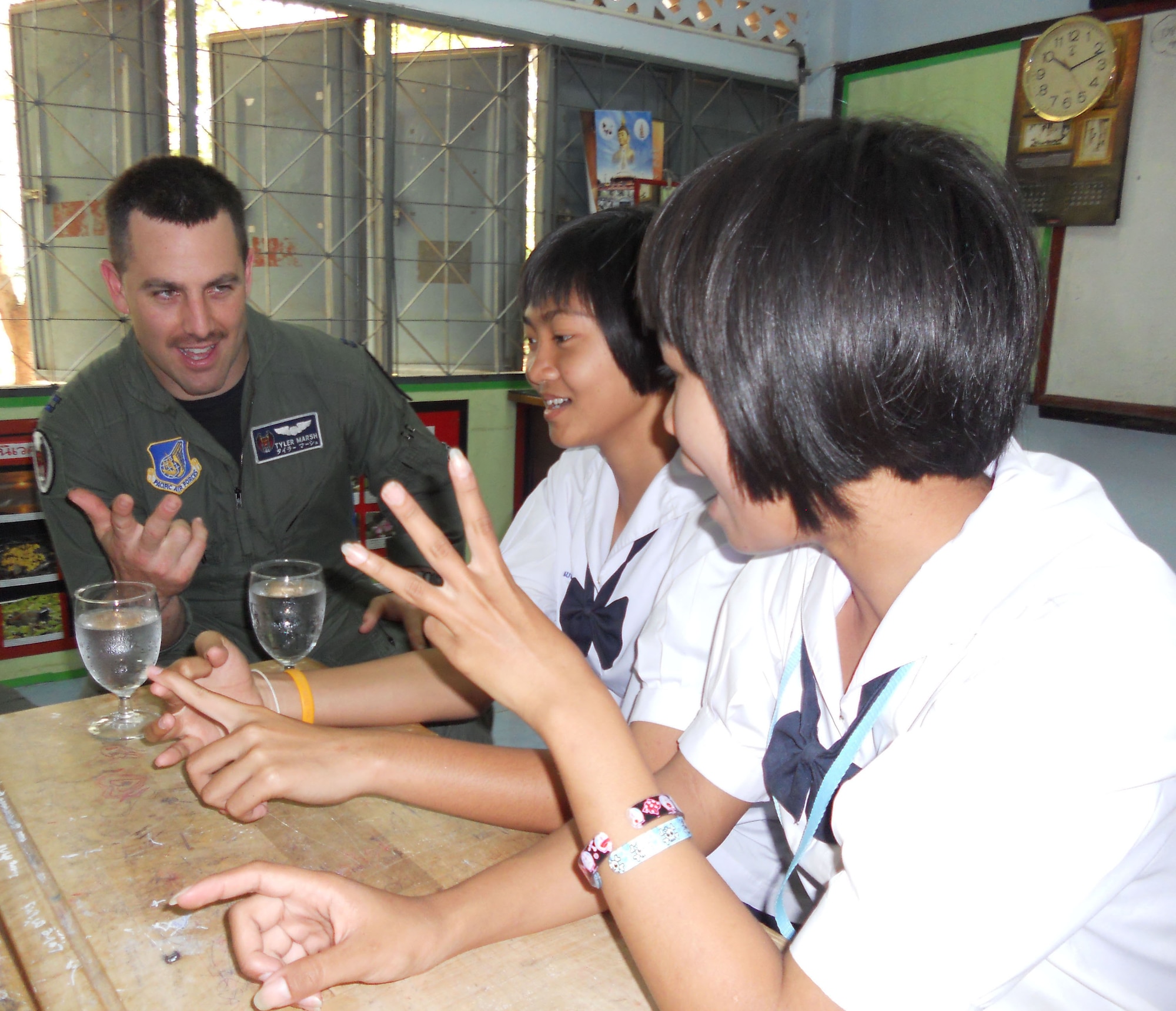 KORAT, Thailand - Capt. Tyler March, an F-15 pilot with the 44th Fighter Squadron at Kadena Air Base, Japan, learns to count in Thai with Pure Wanviag and Tup Benya, students from Ang Huay Yang School in Korat, Thailand, March 14. Airmen visited the school with members of the Royal Thai and Republic of Singapore Air Forces during Cope Tiger 2011, an annual, multilateral, joint field training exercise currently being conducted in Thailand March 14 through 25. (U.S. Air Force Photo/ Capt. Kirsten Udd)