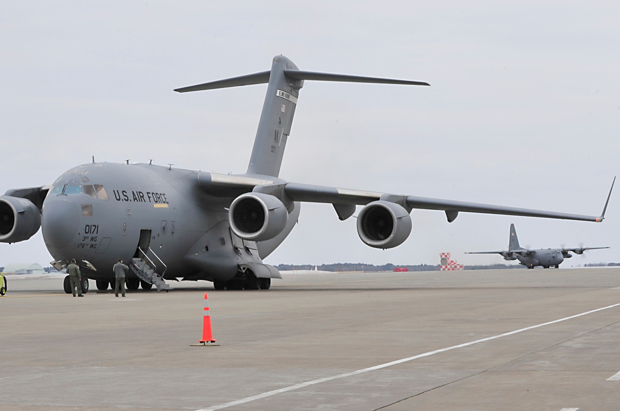 MISAWA AIR BASE, Japan -- A U.S. Air Force C-17 Globe Master III sits on the flight line as a C-130 Hercules taxis in Mar. 15. Misawa's flight line has seen a influx of cargo aircraft since the start of Operation Tomodachi. (U.S. Air Force photo by Staff Sgt. Marie Brown\Released)
