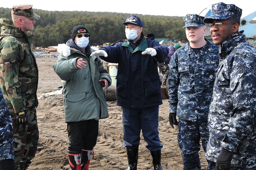 Masayoshi Sawaguchi, director of the Department of Policy and Finance for Misawa Japan, speaks with U.S. Navy sailors during a cleanup effort at the city's fishing port, March 14, 2011.