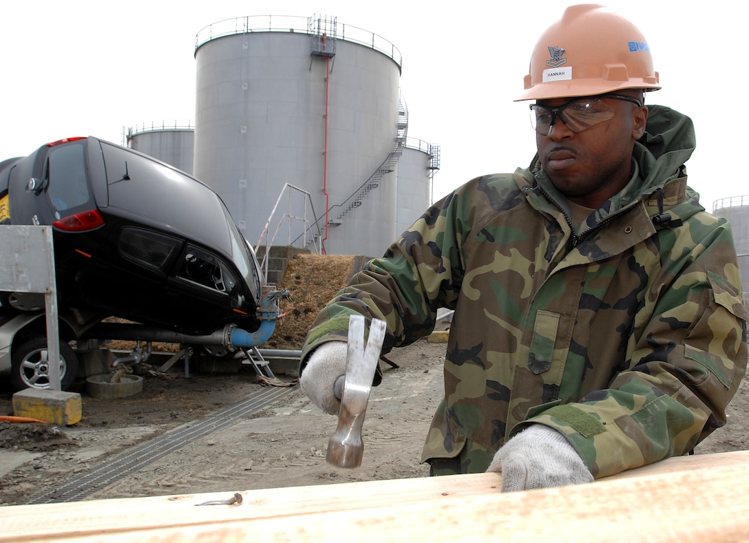U.S. Navy Petty Officer 2nd Class Charles Hannah nails two-by-four planks to reinforce the fence line at the U.S. Fleet and Industrial Supply Center Yokosuka Defense Fuel Support Point Hachinohe in Misawa, Japan, Miarch 15, 2011.
