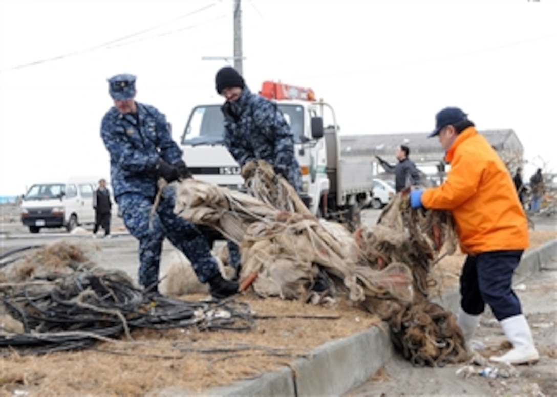 Sailors assigned to Naval Air Facility Misawa help a Misawa City employee transport salvageable fishing equipment at the Misawa Fishing Port on March 15, 2011.  More than 120 sailors and airmen from the air base joined Misawa City workers and members of the community in the relief effort.  