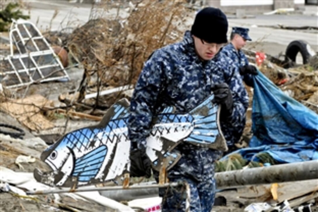 U.S. Navy Seaman Jerad Clymer removes debris from a park at the fishing port in Misawa, Japan, March 15, 2011. More than 120 service members joined Misawa city workers and residents to assist in the relief effort. Clymer is a mineman assigned to Naval Munitions Command East Asia Division Unit Misawa.