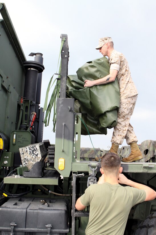 Lance Cpl. Zach Hopkins, motor transport operator with Battery R, 3rd Battalion, 12th Marine Regiment, 3rd Marine Division, III Marine Expeditionary Force, and Lance Cpl. Jacob Winstead, motor transport operator/ on vehicle equipment with Battery R, dress a 7-ton as a flat bed March 16 in preparation for the quadcons it will be transporting when the unit leaves to conduct an exercise in Korea in the upcoming weeks.