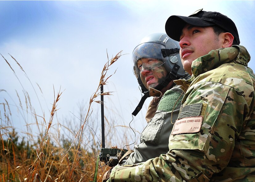 Capt. Miles Newsome, a 25th Fighter Squadron pilot, and Staff Sgt. Emanuel Espino-Mata, a Survival Evasion Restience and Escape specialist, sit and wait for an inbound helicopter during a combat search and rescue scenario in Jeugaun, Republic of Korea, March 16. The evaluation tested Captain Newsome's survival techniques such as gathering all evidence of his landing and concealing it with nearby brush. Then the captain also communicated with an A-10 providing cover for rescue efforts. (U.S Air Force photo/Staff Sgt. Daylena Gonzalez)